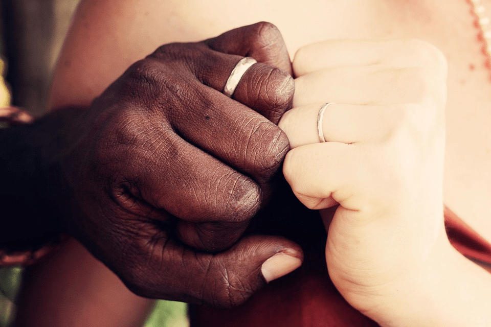 A cross-cultural couple showing their wedding bands