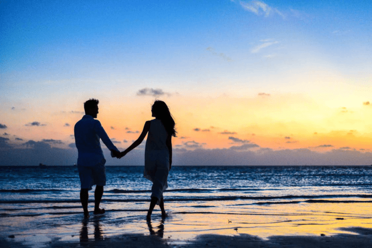 Silhouette of a couple in love holding hands at the sea