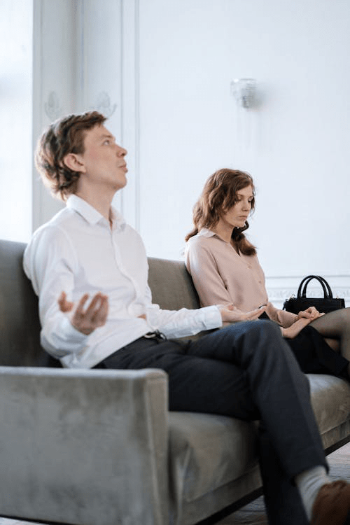 A couple sitting on a couch with a therapist, engaged in a marriage counseling session.