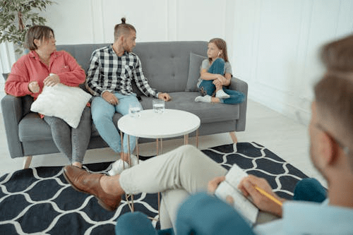 A family of four sitting on a couch in a counseling session