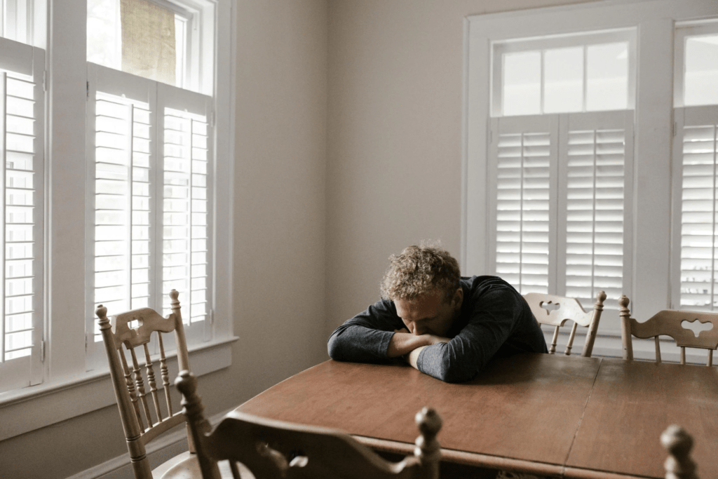 Man sitting on a wooden chair while resting his arms on the table